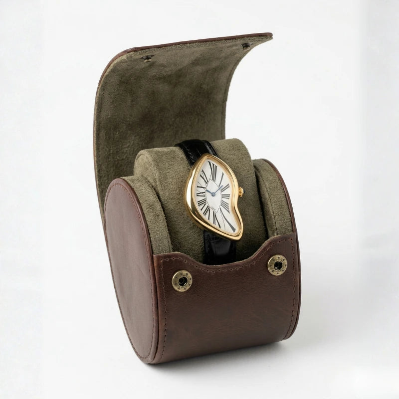 Relógio Fabbricantti Cartti dourado caixa curva mostrador branco romano pulseira couro preto porta-relógio viagem couro marrom em pé fundo branco Quiet Luxury